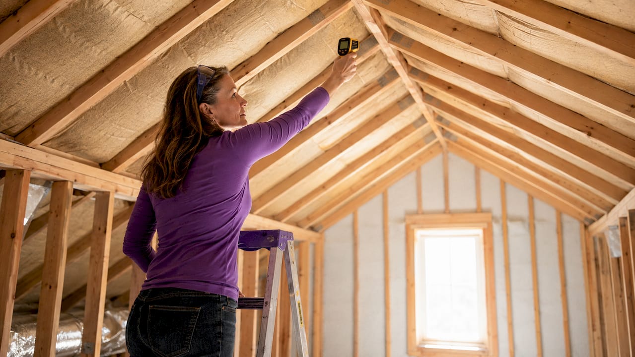 Homeowner inspecting attic insulation temperature