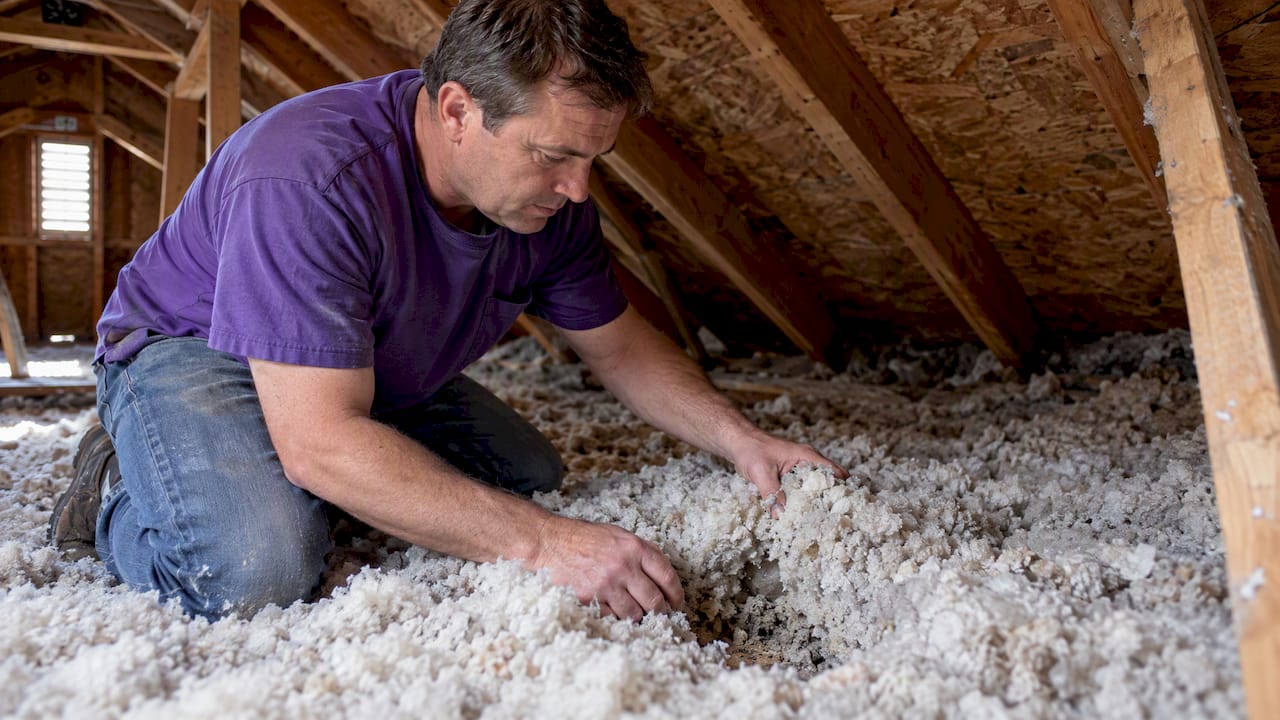 Homeowner checking loose-fill attic insulation condition